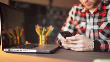 genç adam akıllı telefon ve dizüstü bilgisayar kullanarak evden çalışma.