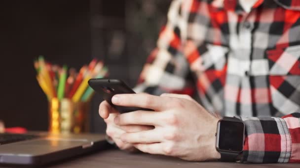 Joven que trabaja desde casa usando el teléfono inteligente y la computadora portátil . — Vídeos de Stock