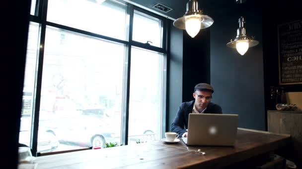 Молодой человек пьет кофе на улице, пользуясь планшетным компьютером — стоковое видео