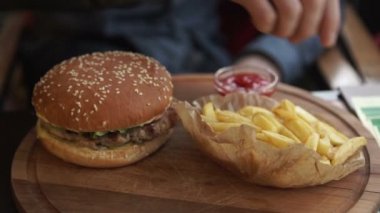 Klasik Amerikan peyniri hamburger ve patates kızartması elinde