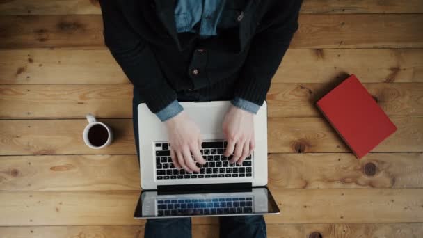 Hombre trabajando en un piso de madera con su portátil, teléfono, tableta y agenda . — Vídeos de Stock