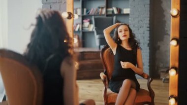 Genç ve güzel bir kadının yansıması makyajını yapıyor, aynaya bakıyor.