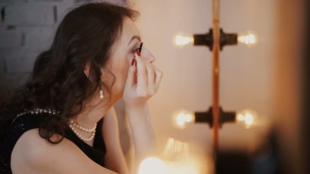 Reflejo de una joven hermosa mujer que se aplica el maquillaje, mirando en un espejo — Vídeos de Stock