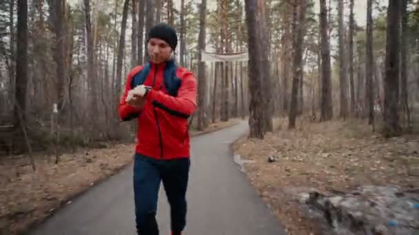 Uomo che corre nel bosco formazione bosco e guardare orologi intelligenti . — Video Stock