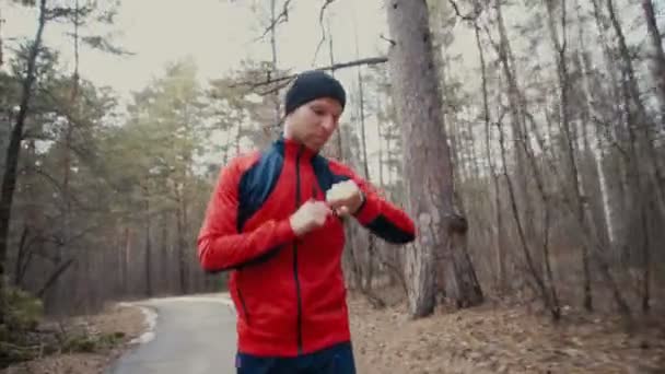 Hombre corriendo en bosques entrenando y mirando relojes inteligentes . — Vídeo de stock