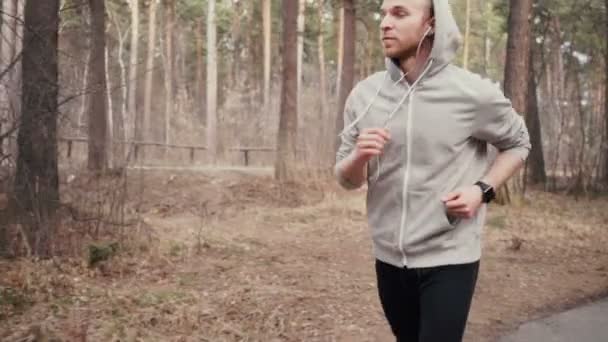 Чоловік бігає в лісі тренування і дивиться на розумні годинники . — стокове відео