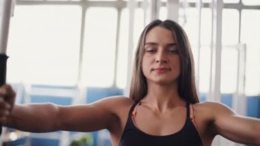 genç kadın kas kablo spor salonu makinede esneme.