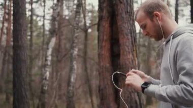 Güneşli sonbahar doğa akıllı telefon ile genç yakışıklı atlet.