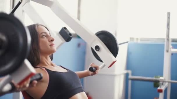 Jonge vrouw buigen spieren op kabel sportschool machine. — Stockvideo