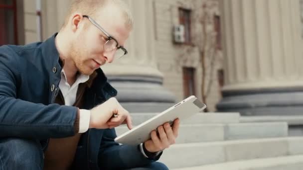 Studente utilizzando un tablet e rivedere per il suo esame mentre seduto — Video Stock