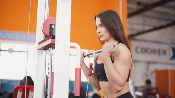 Jonge vrouw buigen spieren op kabel sportschool machine. — Stockvideo