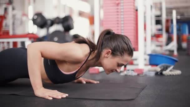 Brunett kvinna på gym driva upp push-up träning motion — Stockvideo