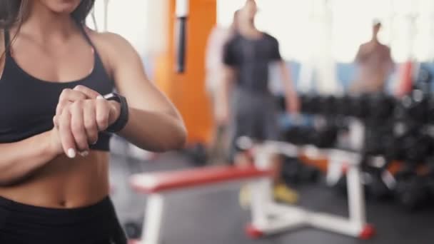 Умные часы, показывающие сердечный ритм тренирующейся женщины в спортзале — стоковое видео