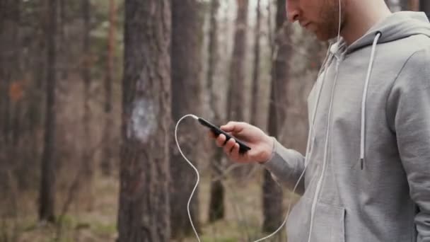 Jeune beau coureur avec téléphone intelligent à l'extérieur dans la nature ensoleillée d'automne . — Video