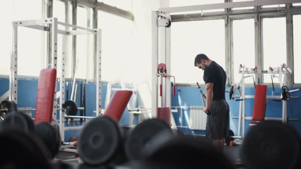 El hombre fuerte - el culturista con las mancuernas en el gimnasio, el ejercicio con la barra — Vídeo de stock