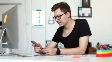 oung adam akıllı telefon ve dizüstü bilgisayar kullanarak evden çalışma