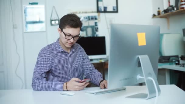 Ooral man aan het werk vanuit huis met behulp van slimme telefoon en laptopcomputer — Stockvideo