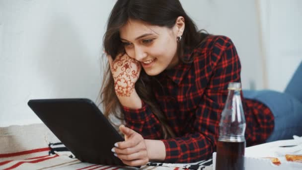 Азиатка ест пиццу и смотрит на цифровой планшетный компьютер дома — стоковое видео