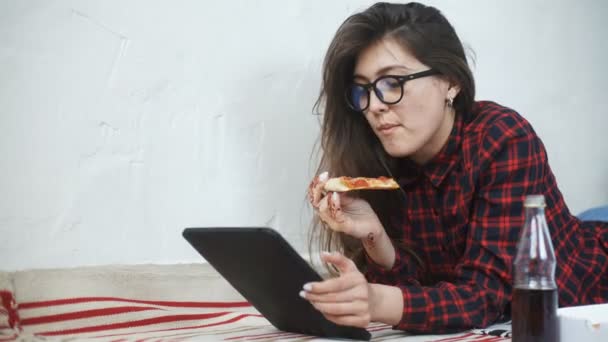 Asiatisk kvinna äta pizza och tittar på en digital tablet dator hemma — Stockvideo