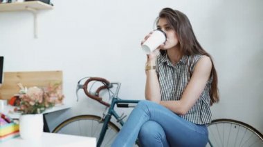 Genç kadın kahve veya çay ve okuma dergi yudumlarken