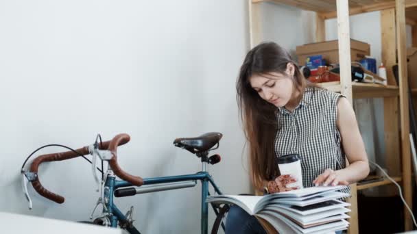 コーヒーまたは紅茶、雑誌を読むをすすりながら若い女性 — ストック動画