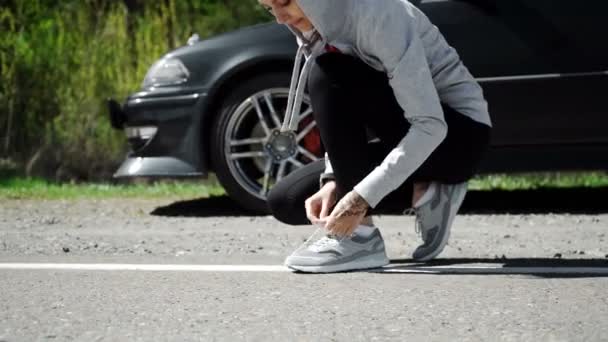 Mujer atando los cordones en sus zapatos de correr mientras está de pie — Vídeos de Stock