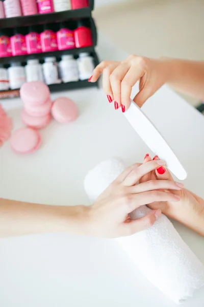 Woman in salon receiving manicure by nail beautician