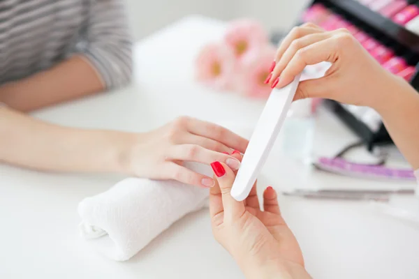 Mulher no salão recebendo manicure por esteticista de unhas — Fotografia de Stock