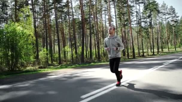 Hombre corriendo mirando su pulso afuera en la naturaleza en la carretera con smartwatch . — Vídeo de stock