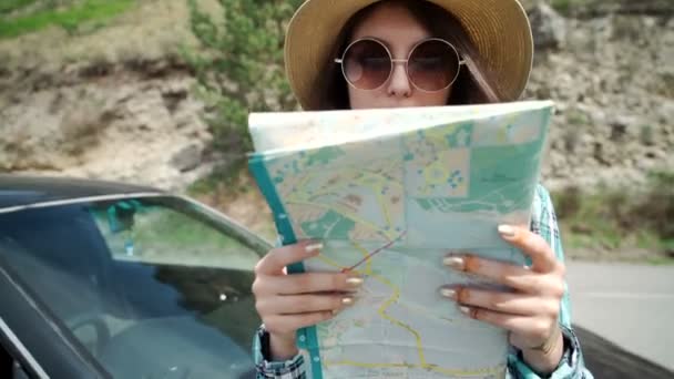 Viaggio - giovane donna con auto guarda la tabella di marcia su una spiaggia contro mare e cielo — Video Stock