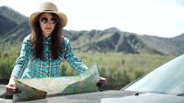 Viaggio - giovane donna con auto guarda la tabella di marcia su una spiaggia contro mare e cielo — Video Stock