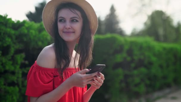 Mujer en vestido rojo sosteniendo un teléfono con monedero móvil aplicación — Vídeo de stock