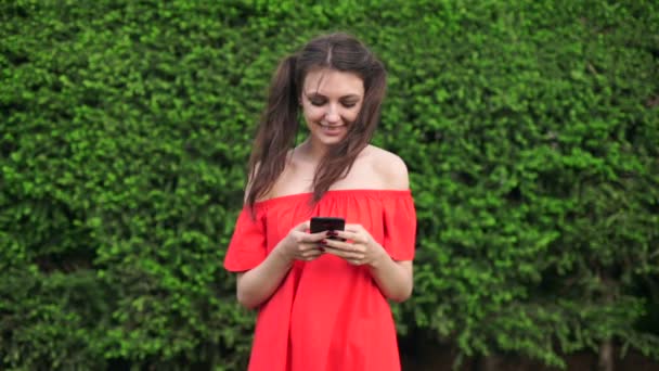 Junge schöne Mädchen auf dem Gras und zeigt in das Telefon — Stockvideo
