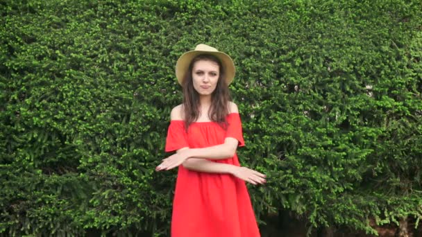 Моторошно. Красива щаслива модель, що стоїть грайливо в червоній сукні на природі — стокове відео