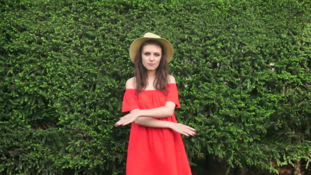 Lento movimiento. Hermosa modelo feliz de pie juguetón en vestido rojo en la naturaleza — Vídeos de Stock