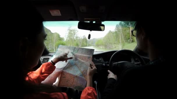 Slowmotion. Πίσω όψη πυροβολισμό από ένα νεαρό ζευγάρι σε οδικό ταξίδι που διαβάζει έναν χάρτη — Αρχείο Βίντεο