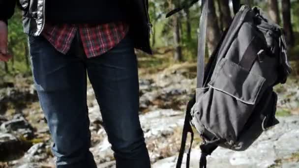 Человек с рюкзаком в руке, идущий по горной дороге — стоковое видео