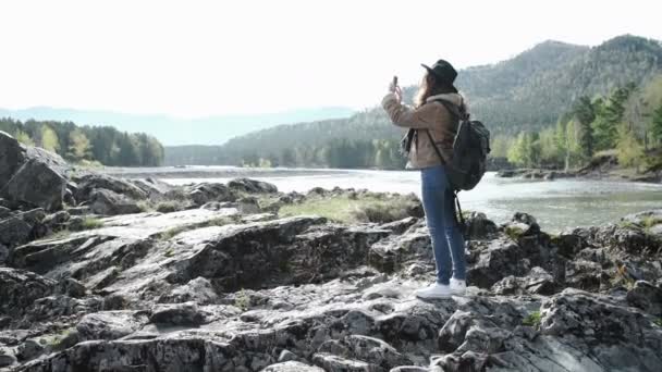 Жінка-хокеїстка робить фотографію зі смартфоном на гірському піку скелі — стокове відео