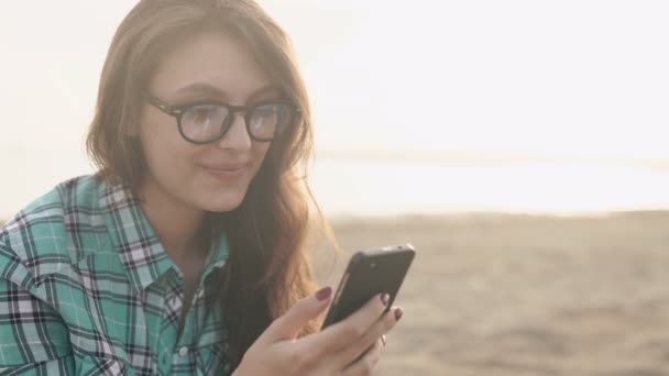 Joven mujer bonita con estilo, manos sosteniendo un teléfono, camisa de mezclilla y jeans — Vídeo de stock