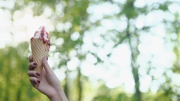 Donna che tiene lo scioglimento del gelato in mano su sfondo luce estate natura — Video Stock