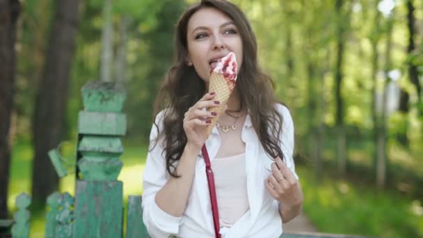 Portrait de jeune femme heureuse mangeant de la glace, en plein air — Video