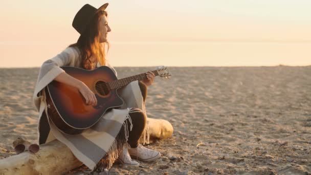 Güzel genç bir kadın sahilde gitar çalıyor. — Stok video
