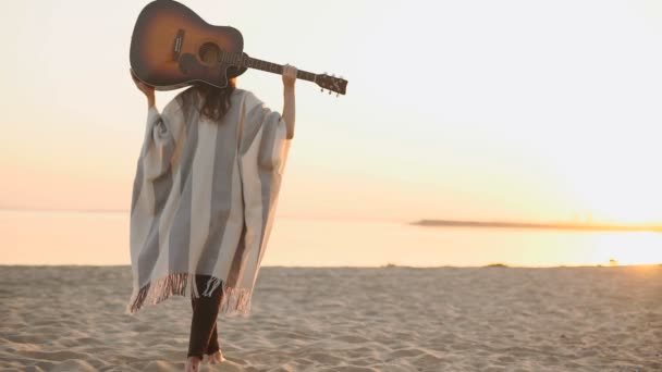 Mujer de vuelta caminando en la playa con la guitarra — Vídeos de Stock