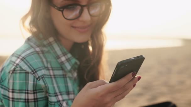 Joven mujer bonita con estilo, manos sosteniendo un teléfono, camisa de mezclilla y jeans — Vídeo de stock