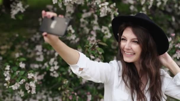 Boldog asszony selfie véve a tabletta a virágzó kert. — Stock videók