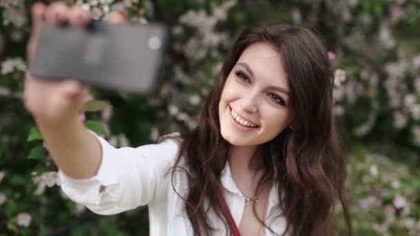 Mujer feliz tomando selfie en la tableta en el jardín floreciente . — Vídeos de Stock