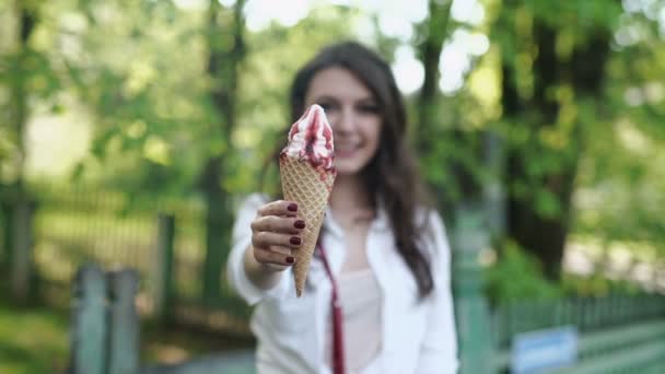 Медленное движение. Портрет молодой счастливой женщины, кушающей мороженое на открытом воздухе — стоковое видео