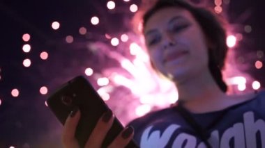 Kız kullanım akıllı telefon, havai fişek gibi bir arka plan görüntüsü.
