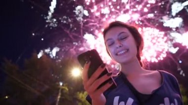 Kız kullanım akıllı telefon, havai fişek gibi bir arka plan görüntüsü.