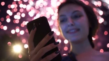 Kız kullanım akıllı telefon, havai fişek gibi bir arka plan görüntüsü.